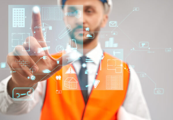 Close up of architect wearing reflective vest and helmet. Selective focus of digital tactile charts screen, man touching virtual icon on projection. Concept of digitalization, construction.