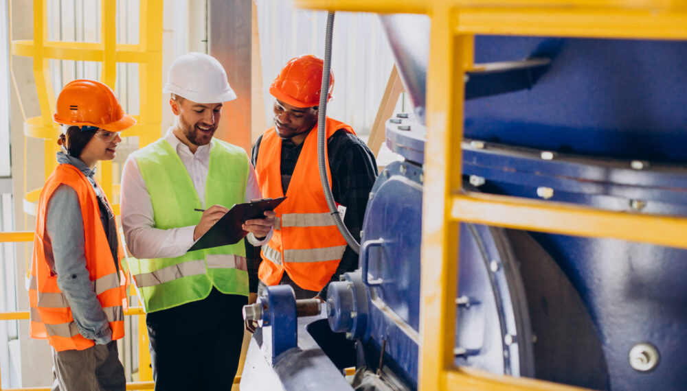 Three people discussing a plan at a factory