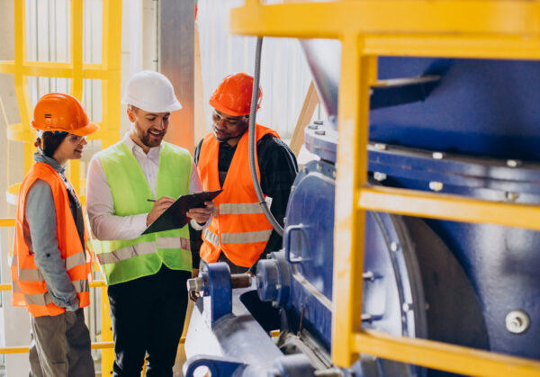 Three people discussing a plan at a factory